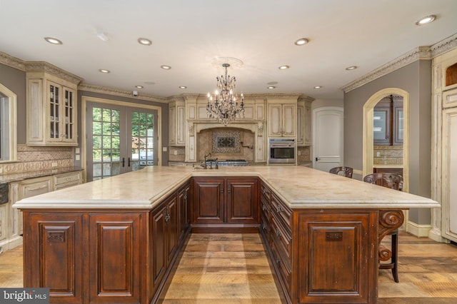 kitchen featuring oven, cream cabinets, pendant lighting, a large island, and a kitchen bar