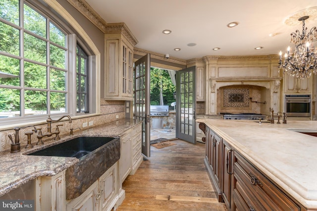 kitchen with hardwood / wood-style flooring, a healthy amount of sunlight, hanging light fixtures, and a chandelier