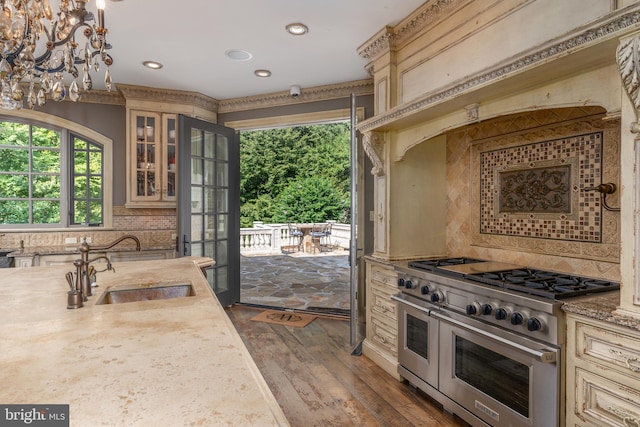 kitchen with range with two ovens, dark wood-type flooring, decorative light fixtures, sink, and decorative backsplash