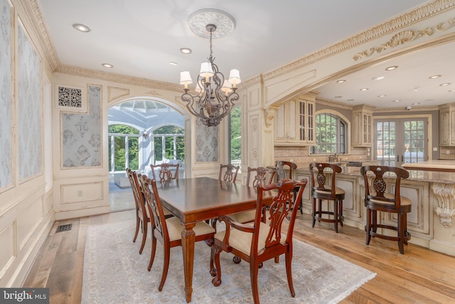 dining space featuring ornamental molding, a wealth of natural light, a chandelier, and light hardwood / wood-style flooring