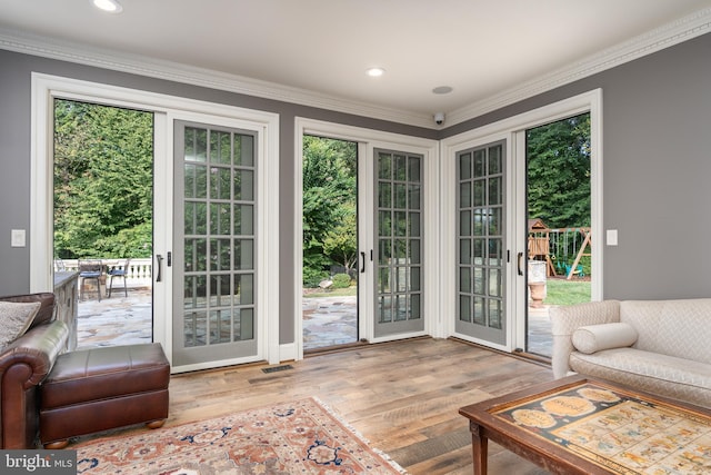 entryway with light wood-type flooring, crown molding, and plenty of natural light