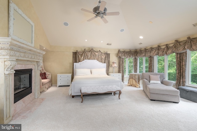 carpeted bedroom with high vaulted ceiling, multiple windows, ceiling fan, and a tile fireplace