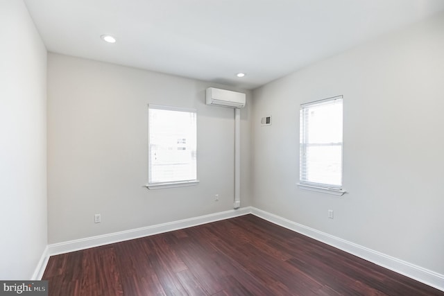 unfurnished room with wood-type flooring and a wall unit AC