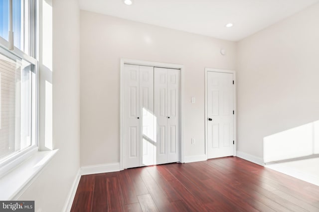 unfurnished bedroom featuring multiple windows and dark hardwood / wood-style flooring