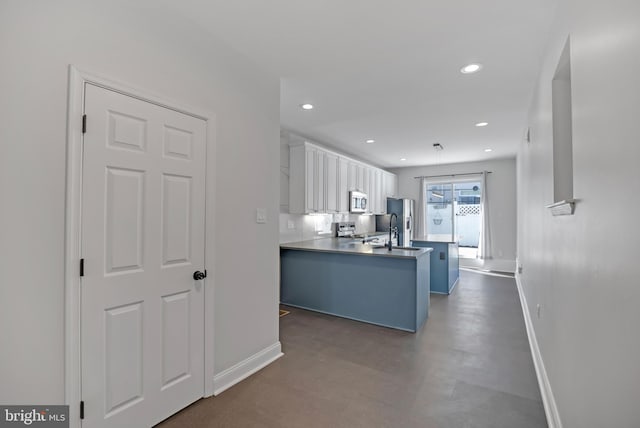 kitchen featuring sink, kitchen peninsula, a kitchen breakfast bar, white cabinetry, and stainless steel appliances