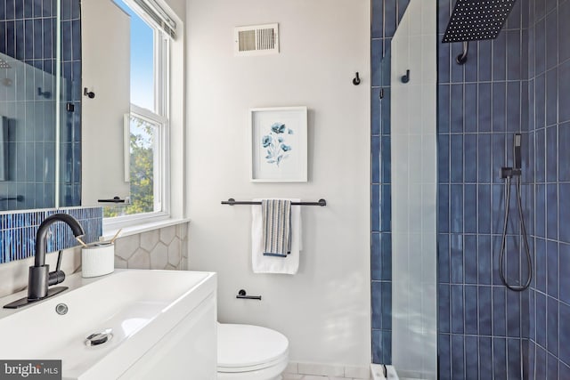 bathroom featuring vanity, a tile shower, and toilet