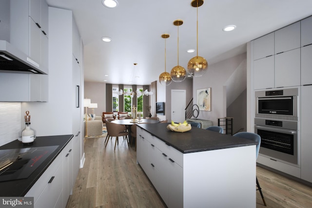 kitchen with pendant lighting, wood-type flooring, white cabinetry, a kitchen breakfast bar, and a center island