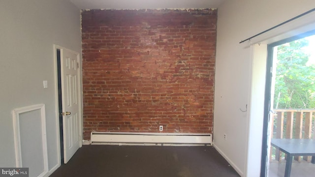 unfurnished room featuring baseboard heating and brick wall