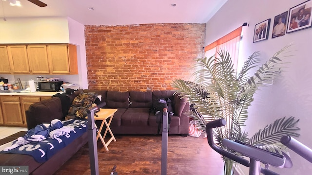 living room featuring ceiling fan and brick wall