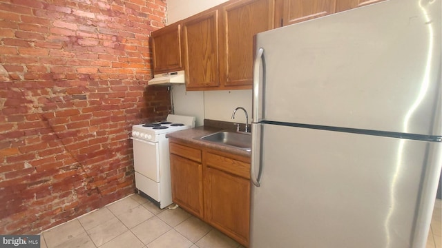 kitchen with brick wall, white range oven, sink, light tile patterned floors, and stainless steel refrigerator