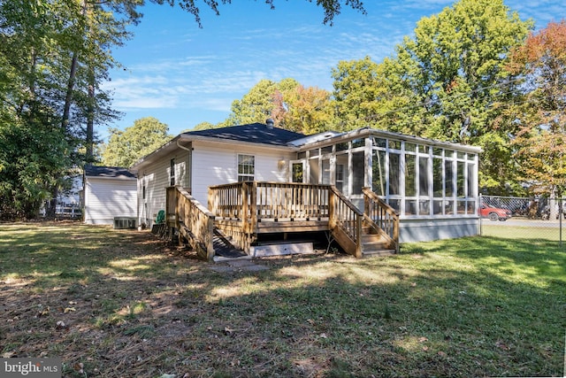 back of house with central air condition unit, a sunroom, a lawn, and a wooden deck