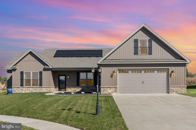 view of front facade with a yard, solar panels, and a garage