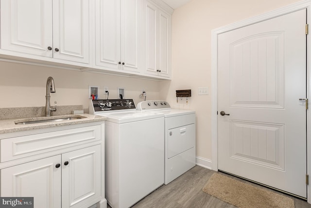 clothes washing area featuring sink, light hardwood / wood-style flooring, separate washer and dryer, and cabinets