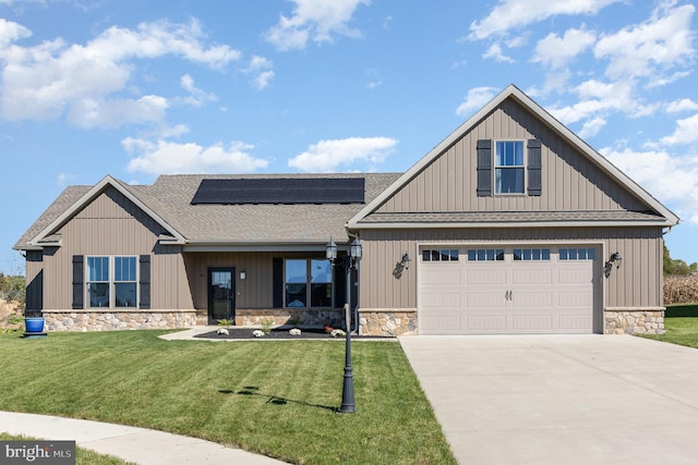 view of front of property with a front yard, solar panels, and a garage