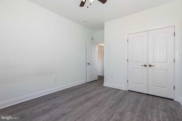 unfurnished bedroom with a closet, dark hardwood / wood-style floors, and ceiling fan