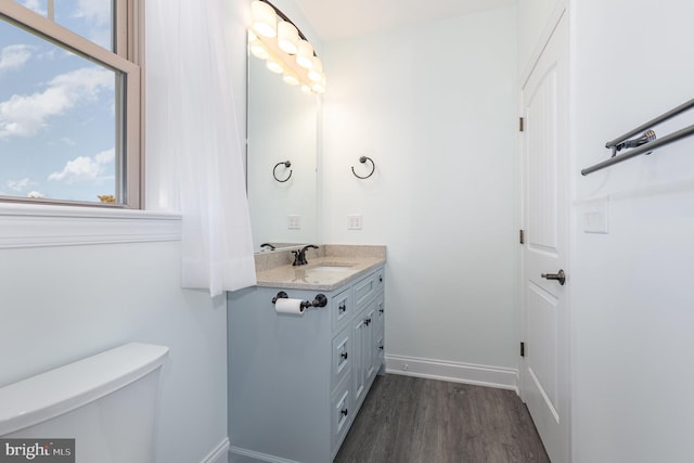 bathroom featuring toilet, a healthy amount of sunlight, vanity, and hardwood / wood-style flooring