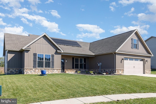 view of front facade with a front yard, a garage, and solar panels