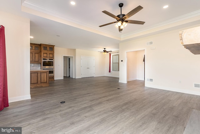 unfurnished living room with crown molding, a tray ceiling, wood-type flooring, and ceiling fan