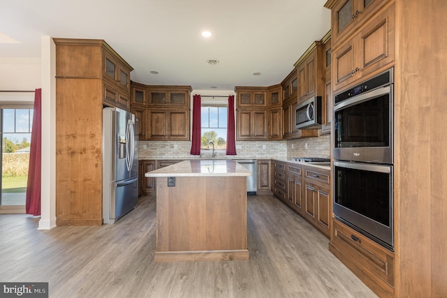 kitchen featuring a center island, stainless steel appliances, light wood-type flooring, and backsplash