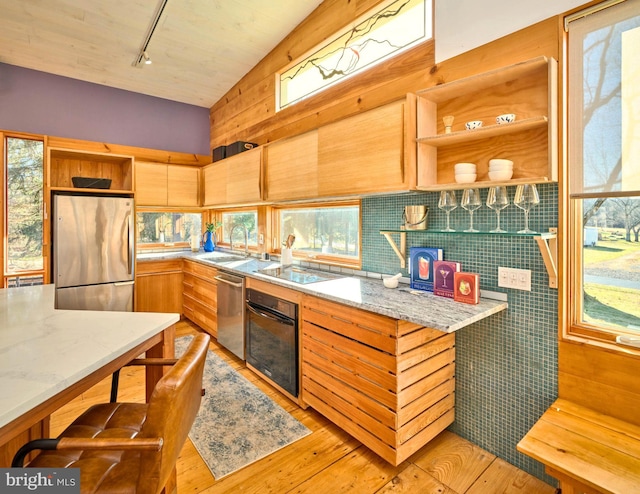 kitchen featuring track lighting, sink, light stone countertops, light wood-type flooring, and appliances with stainless steel finishes