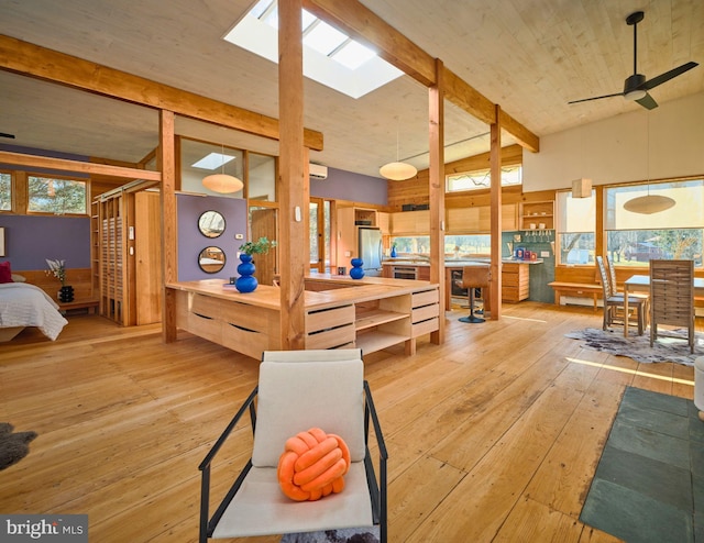 living room with a skylight, ceiling fan, and light hardwood / wood-style flooring