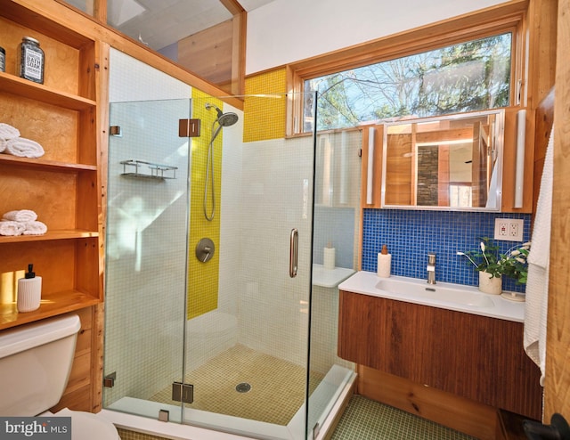 bathroom featuring vanity, toilet, a shower with door, and tasteful backsplash