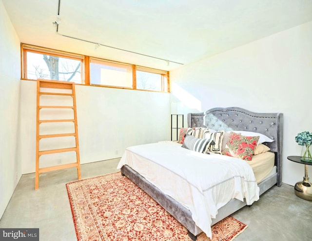 bedroom featuring concrete floors and rail lighting