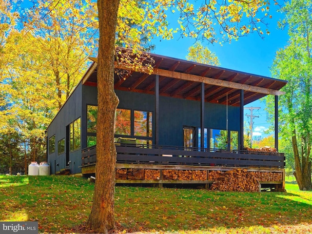 rear view of house featuring a lawn and a deck