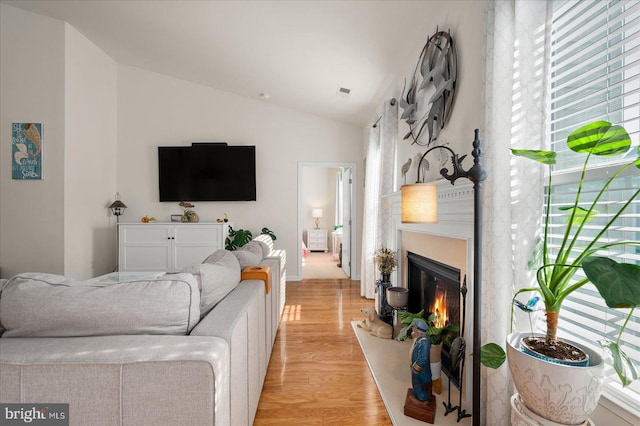 living room with light wood-type flooring and vaulted ceiling