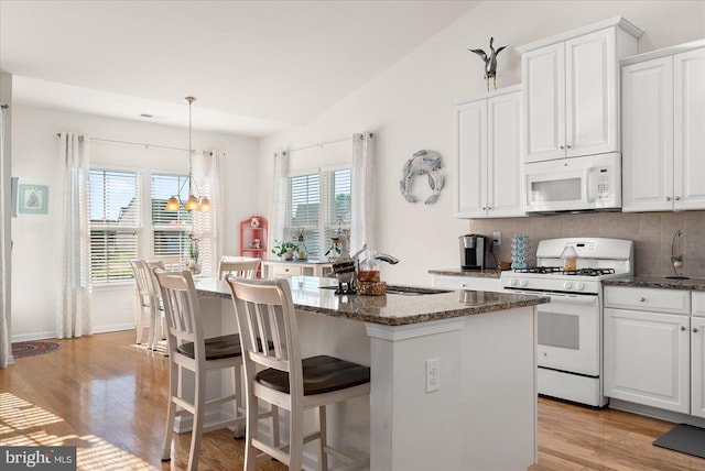 kitchen with white cabinetry, lofted ceiling, and white appliances