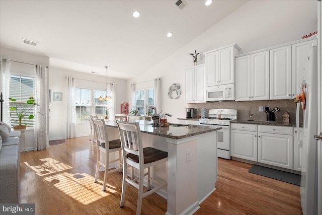 kitchen with white cabinetry, white appliances, decorative light fixtures, and light hardwood / wood-style floors