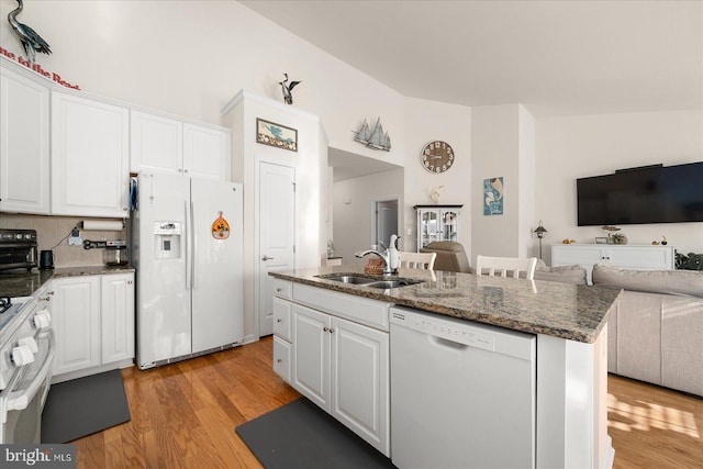 kitchen featuring white cabinets, white appliances, a center island with sink, and light hardwood / wood-style floors