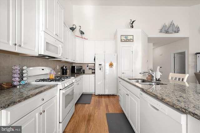 kitchen with stone countertops, sink, white appliances, light hardwood / wood-style flooring, and white cabinets