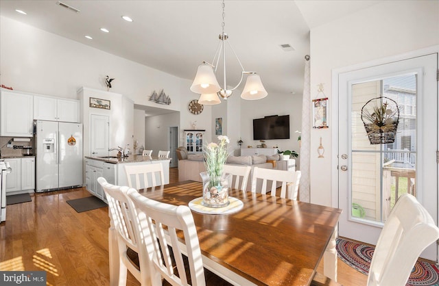 dining area with light hardwood / wood-style floors, sink, an inviting chandelier, and vaulted ceiling