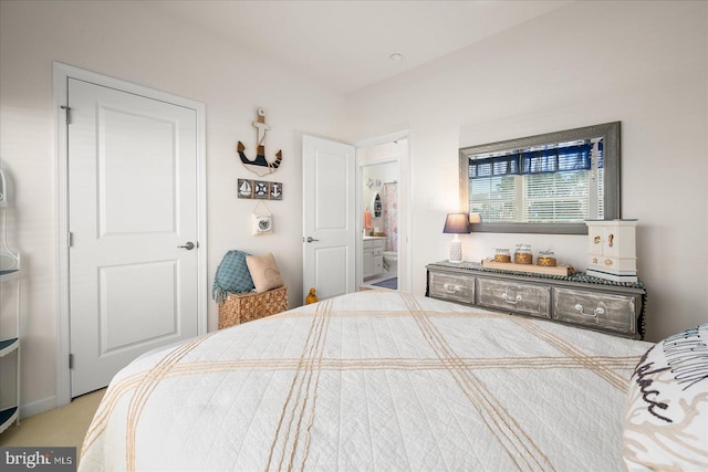 bedroom featuring ensuite bathroom and light carpet