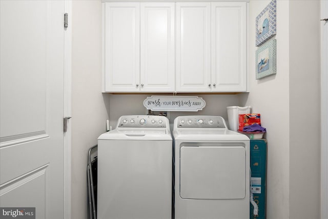 clothes washing area with cabinets and washing machine and clothes dryer