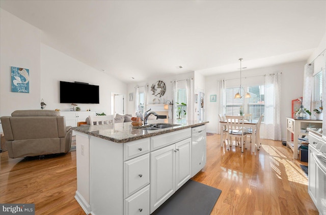 kitchen with light hardwood / wood-style floors, a center island with sink, sink, white cabinets, and dishwasher