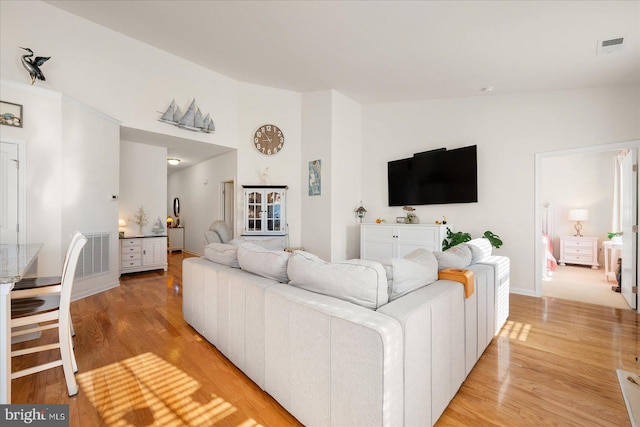 living room with light hardwood / wood-style floors and high vaulted ceiling