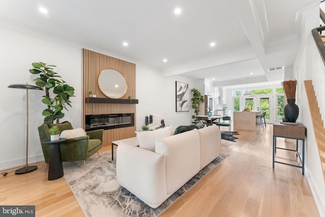 living room featuring beamed ceiling, french doors, light hardwood / wood-style flooring, and ornamental molding