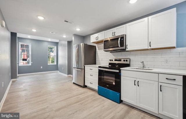 kitchen with light hardwood / wood-style flooring, stainless steel appliances, sink, and white cabinetry