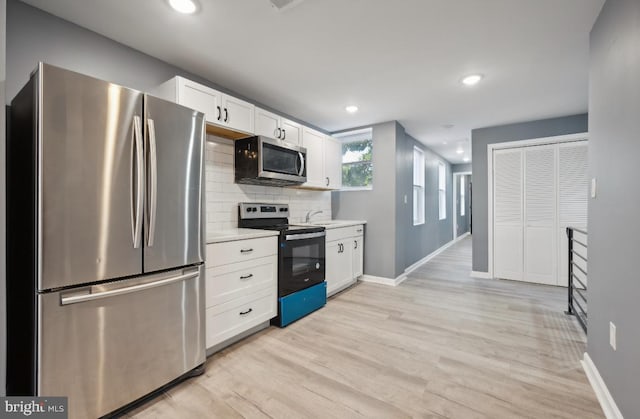 kitchen with stainless steel appliances, white cabinets, tasteful backsplash, and light wood-type flooring