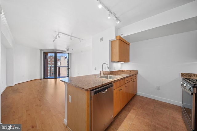 kitchen featuring track lighting, kitchen peninsula, sink, light wood-type flooring, and appliances with stainless steel finishes