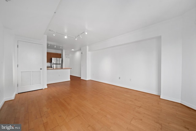 unfurnished living room with rail lighting and light hardwood / wood-style flooring