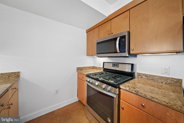 kitchen with appliances with stainless steel finishes, light stone counters, and light tile patterned floors