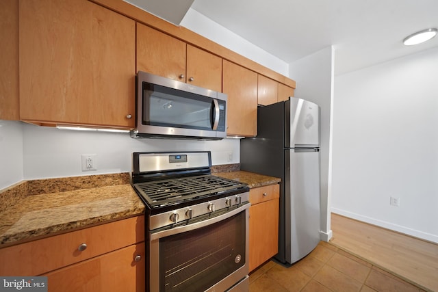 kitchen featuring stone countertops, appliances with stainless steel finishes, and light tile patterned floors