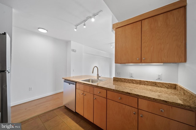 kitchen with track lighting, light stone countertops, light hardwood / wood-style flooring, sink, and stainless steel appliances