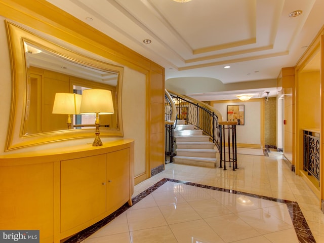 corridor with a raised ceiling and light tile patterned floors