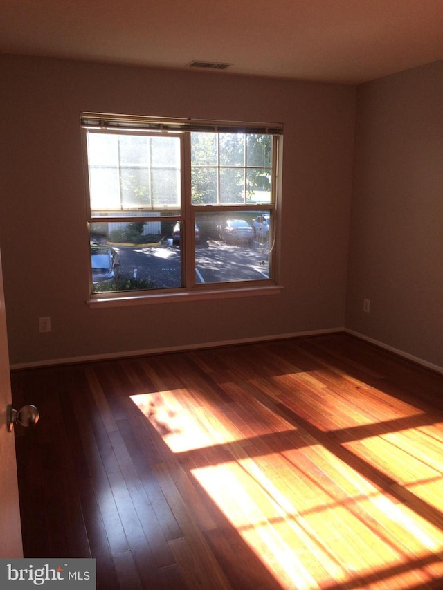 empty room with hardwood / wood-style flooring and plenty of natural light