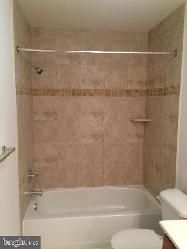 full bathroom featuring vanity, tiled shower / bath, and toilet