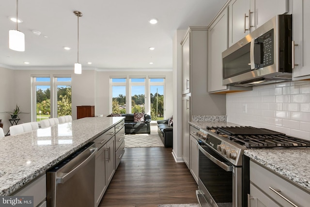 kitchen featuring appliances with stainless steel finishes, a wealth of natural light, and decorative light fixtures